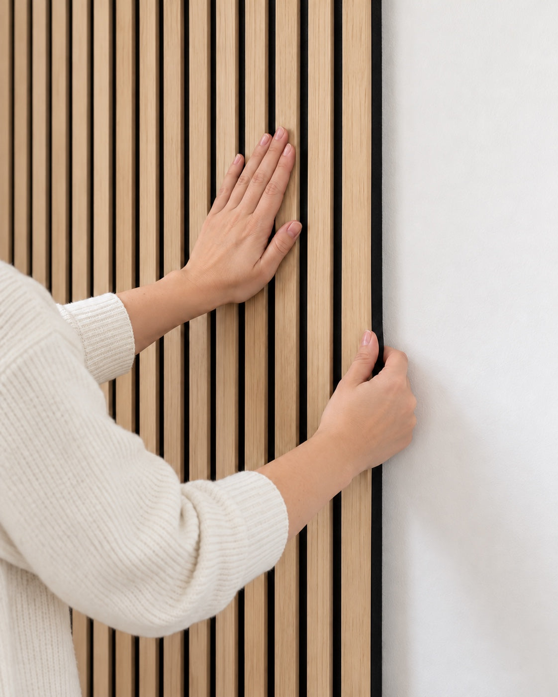 Hands aligning and pressing a light oak slat panel into place on an interior wall.